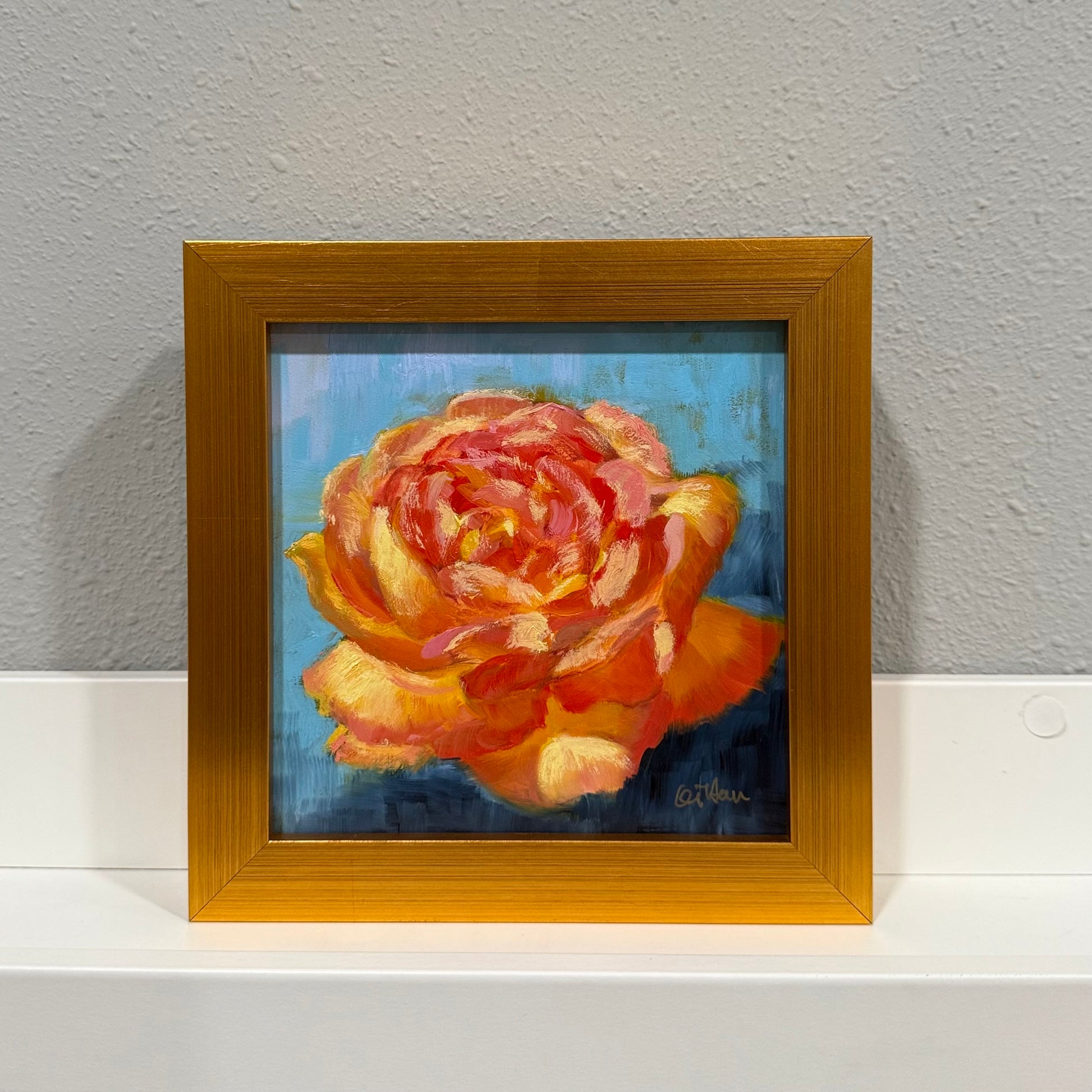 Framed painting of a rose on a gray wall