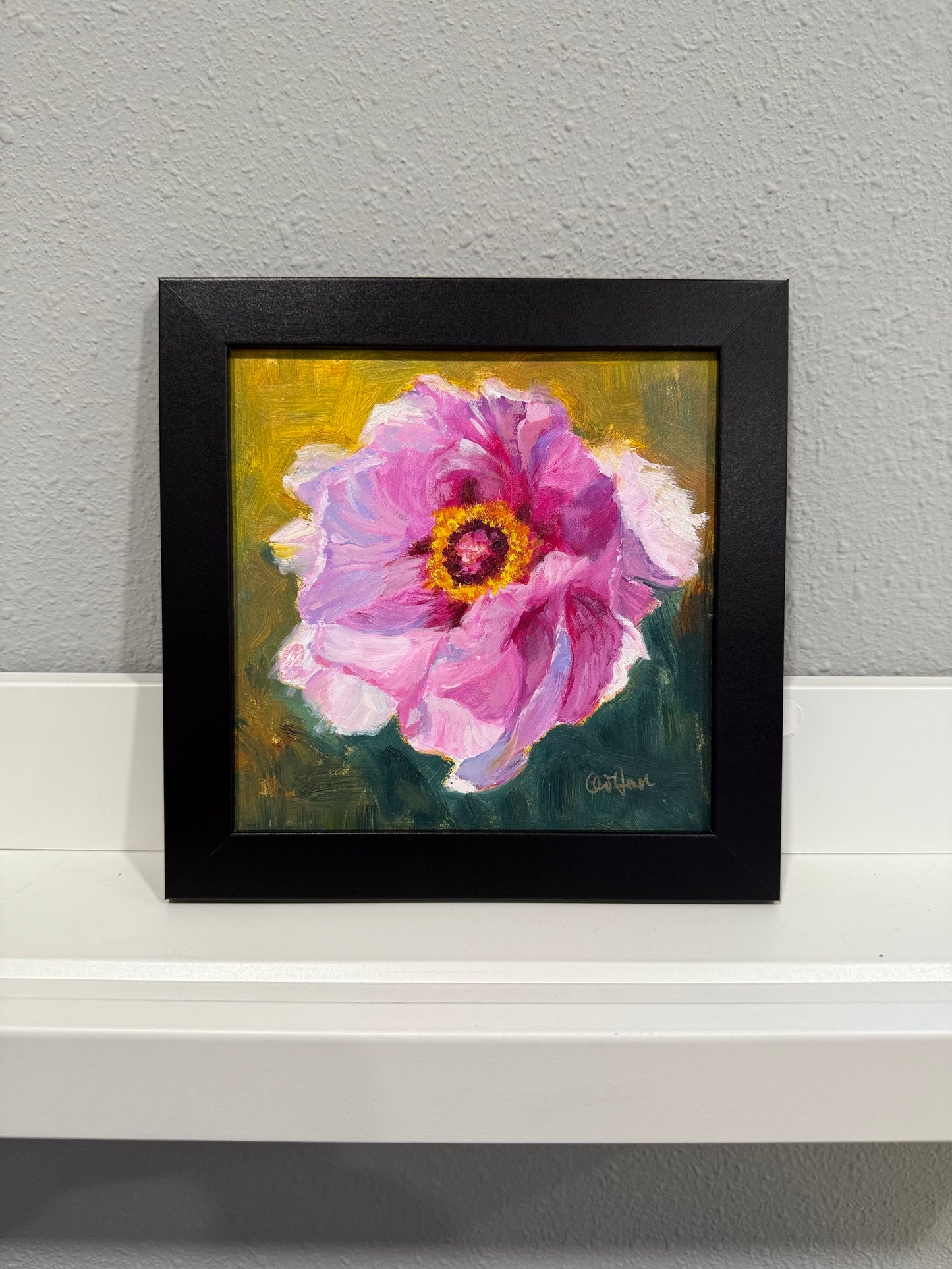 Framed painting of a pink flower on a gray wall
