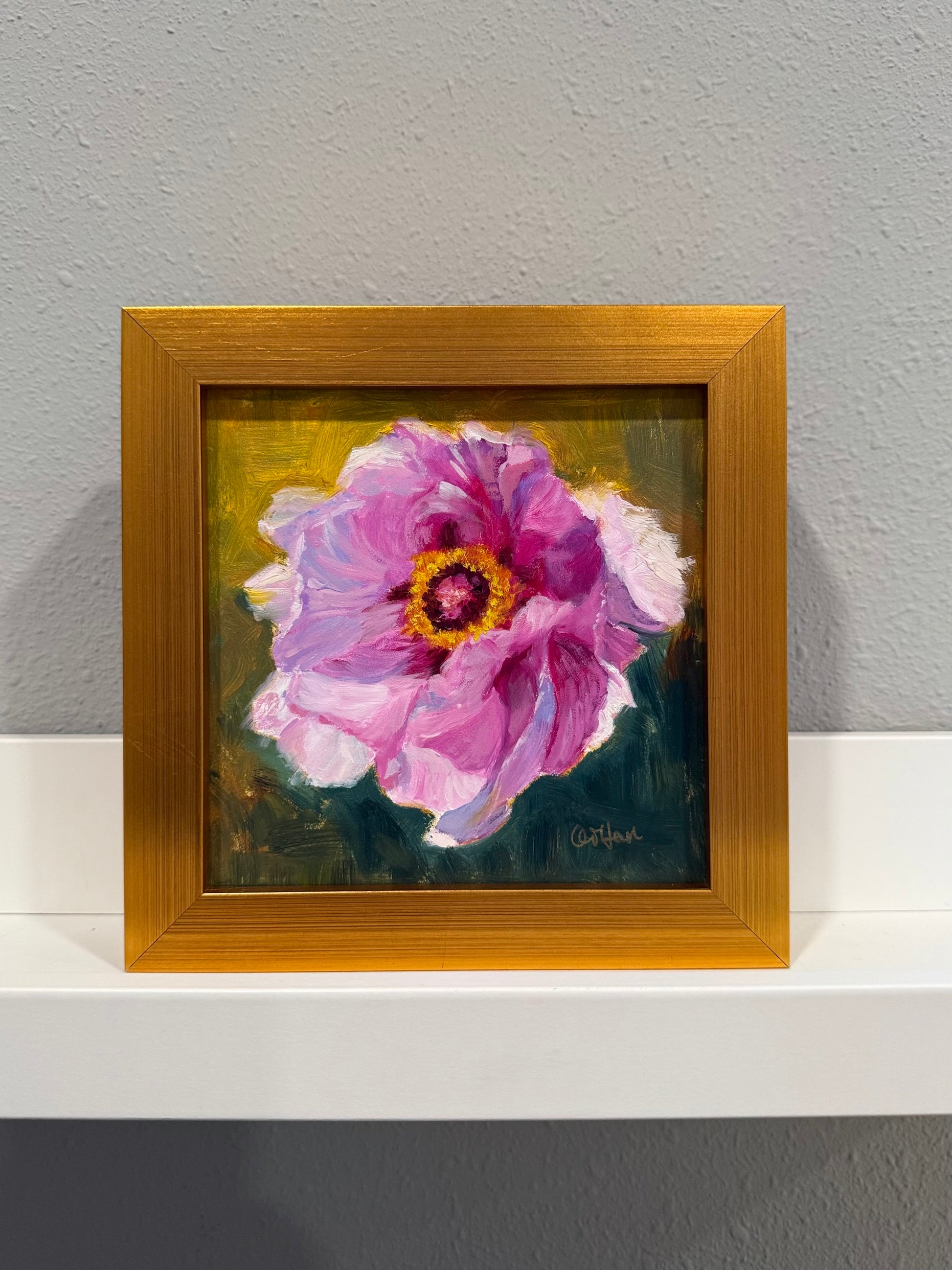 Framed painting of a pink flower on a gray wall