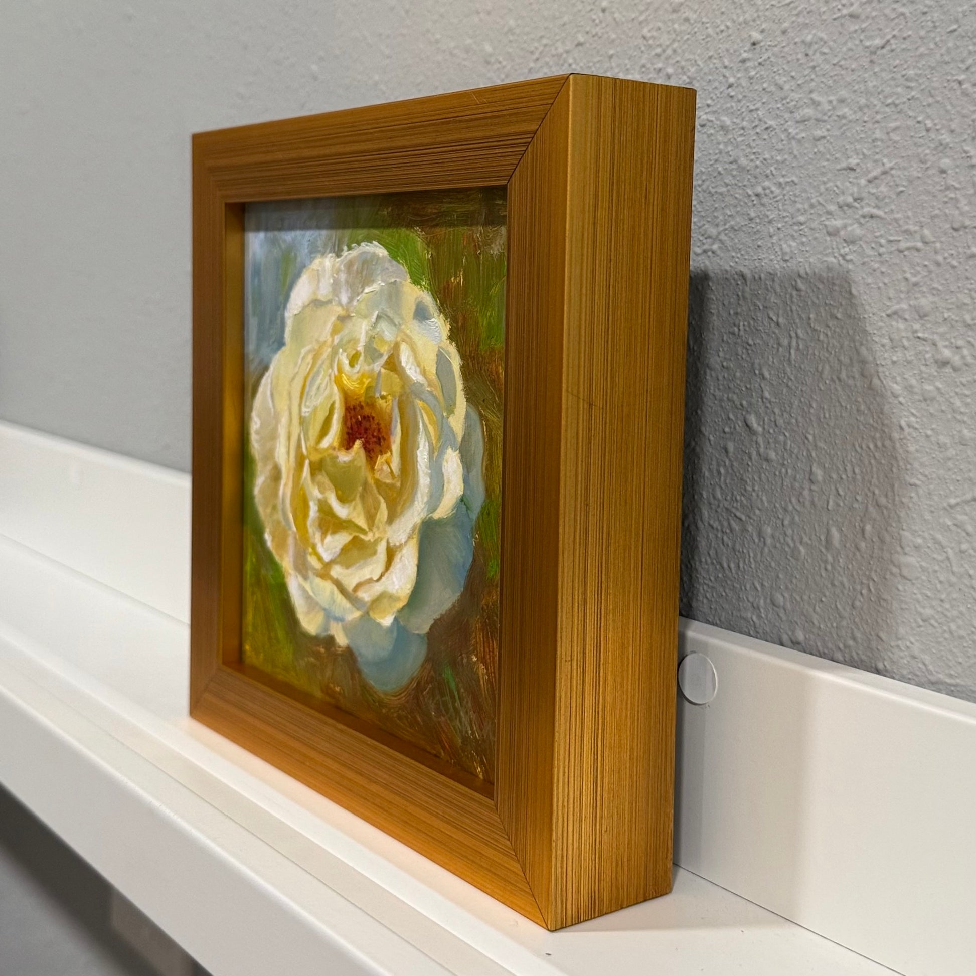 Framed artwork of a white flower on a gray wall