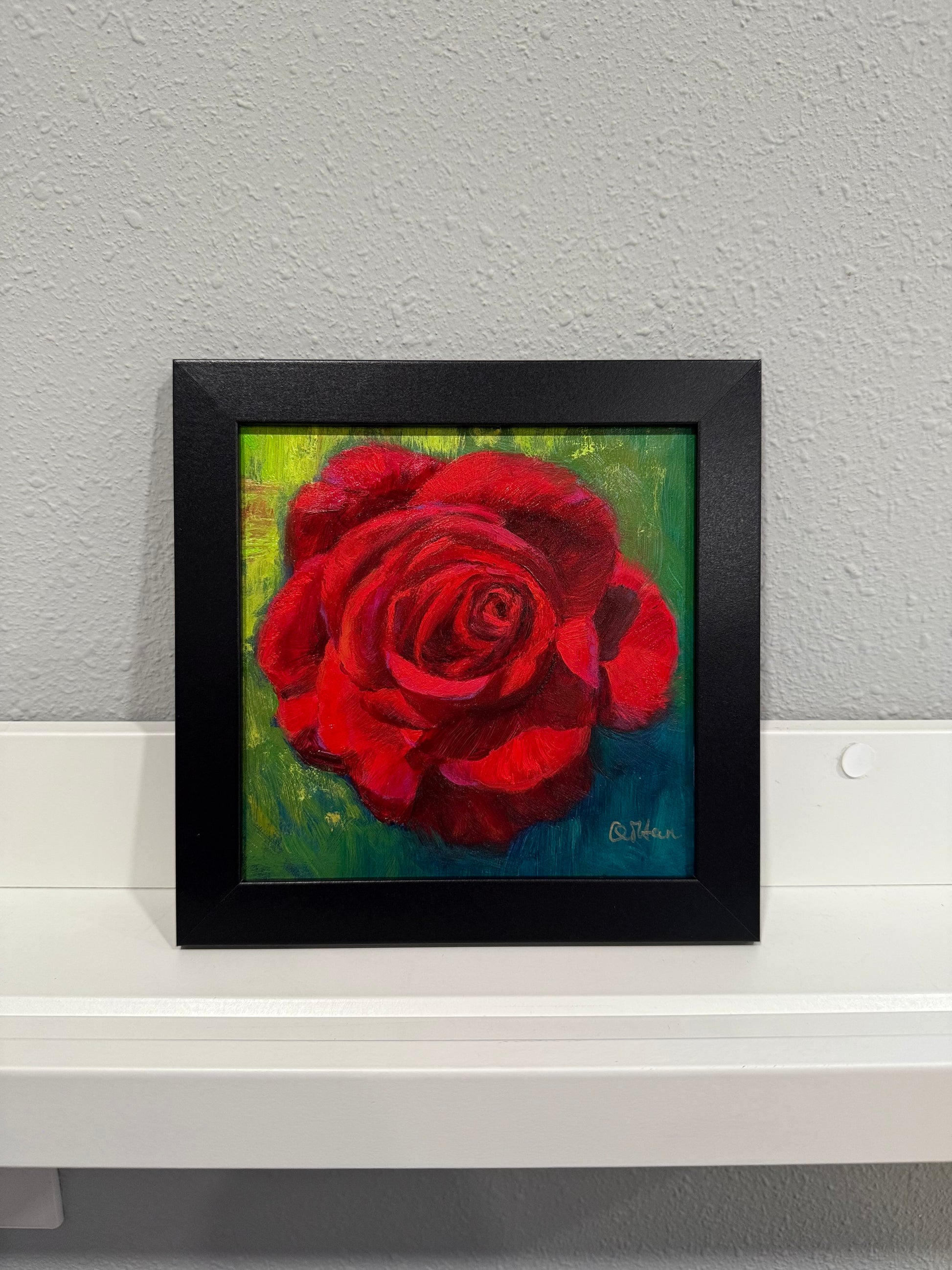 Framed painting of a red rose on a gray wall
